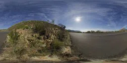 Outdoor HDR panorama featuring a sunny sky over a road with rocky terrain for realistic scene lighting.