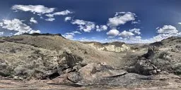 360-degree panoramic HDR image featuring a rugged mountain landscape under a vast blue sky with fluffy clouds.