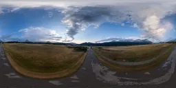 360-degree HDR panorama of a vibrant sunrise with clouds over a serene mountainous road.