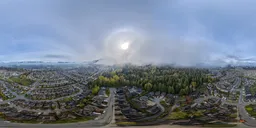360-degree HDR image featuring a sunlit foggy morning over a suburban landscape with lush greenery and mountain backdrop.