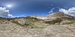 360-degree panoramic HDR image featuring a clear blue sky, sunny mountain terrain, and a tranquil lake for realistic scene lighting.