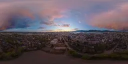 360 aerial HDR panorama of twilight cityscape with stormy sunset clouds.