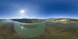 360-degree HDR panorama of a tranquil valley with river, clear blue sky, and mountain backdrop for realistic scene lighting.