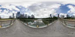 360-degree HDR panorama for scene lighting featuring overcast sky, urban skyline, and lush greenery around a pedestrian bridge.