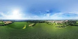 360-degree panoramic HDR image of serene green fields under a blue sky with clouds for realistic lighting in 3D scenes.