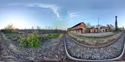 360-degree HDR panorama featuring curved railway lines leading to an abandoned train station with a clear sky.