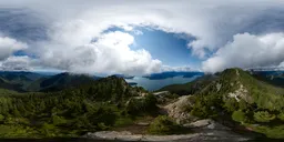 360-degree HDR panorama of a sunny mountain landscape with clouds over a coastal region.