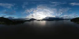360-degree HDR panorama of sunset over water with mountains and clouds for 3D scene lighting.