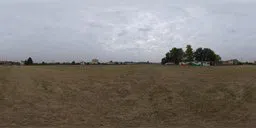 360-degree HDR panorama of a cloudy sky over a suburban open field with sparse buildings.