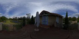 Detailed 360-degree HDR panorama for realistic lighting featuring a house balcony, umbrella, and cloudy sky.