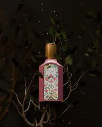 3D-rendered bottle with floral design showcased amid dark leaves for product visualization in Blender.