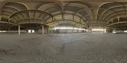 360-degree High Dynamic Range image of an empty industrial bus depot with arched ceiling and natural lighting.