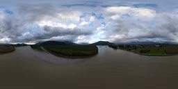 360-degree HDR panorama capturing a river flanked by mountains under a moody cloudy sky at sunset.