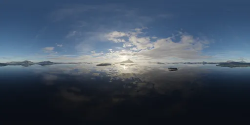 Dynamic aerial HDR panorama featuring sunlit clouds over a serene mountainous region with reflective waters.
