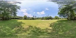 360-degree panoramic HDR image featuring a vibrant blue sky with fluffy clouds over a serene park with lush greenery and distant urban skyline.