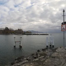 Dynamic cloudscape over calm lake with rocky shore and pier, ideal for realistic lighting in 3D scenes.