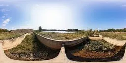 Daylit HDR scene with empty concrete pools by a river, overgrown foliage, and clear skies for realistic lighting setup.