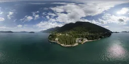 Aerial HDR panoramic showing sunny coastal terrain with ocean and mountains for scene lighting.