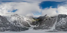 Aerial HDR panorama of snow-capped mountains under a cloudy sky for scene illumination.