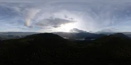 Aerial HDR panorama of mountainous terrain under a sunset sky with expansive clouds, ideal for scene lighting.