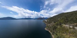 Aerial sunny HDR panorama of a serene Canadian coastal mountain landscape with dynamic cloud formations.