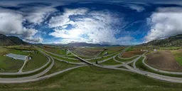360 HDR panoramic image of a scenic valley and highway intersection with cloudy skies and distant mountains.