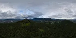 Aerial HDR panorama with dramatic clouds over lush green landscape and mountains at sunset in British Columbia.