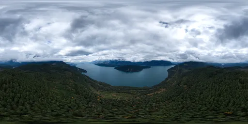 Aerial HDR panorama featuring cloudy skies above a serene mountain lake surrounded by lush forests.