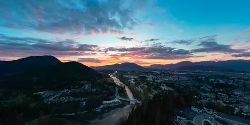 Dramatic sky illuminates river and mountains at dusk in British Columbia, perfect for scene lighting.