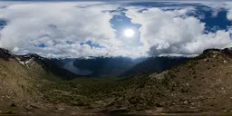 Dynamic aerial HDR panorama for scene lighting featuring mountain terrain, clouds, and sunlight.