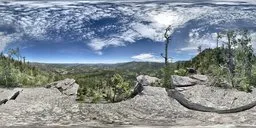 Panoramic HDR image of a scenic landscape with a lone tree, rocky terrain and expansive blue sky for realistic lighting in 3D scenes.