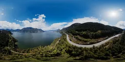 360-degree HDR panorama for lighting with clear skies, mountainous terrain, and vibrant greenery beside a lake.